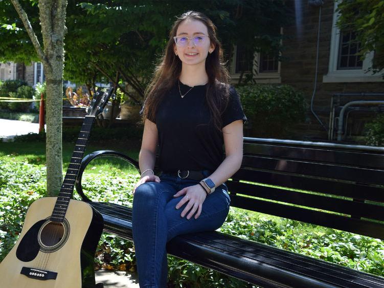 宾州州立大学阿宾顿分校毕业生凡妮莎·塞克斯顿拿着吉他摆姿势